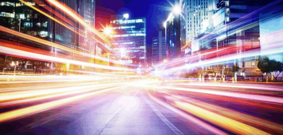 Blurred light trails in a vibrant cityscape at night, symbolizing speed, scale, and digital media momentum.