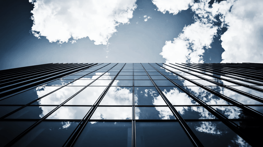 Upward view of a modern glass skyscraper reflecting the sky, symbolizing growth, scalability, and vision.